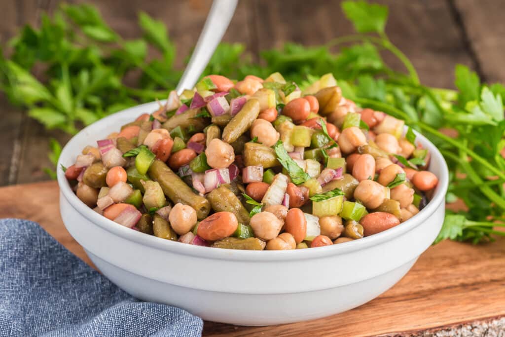 The bean salad in a white bowl with a spoon.