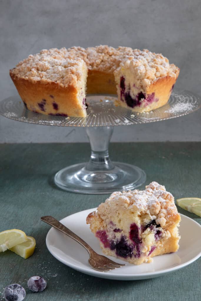 The cake on the dish with a slice on a white plate.