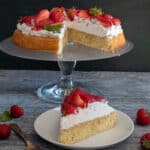 Strawberry crostata on a glass plate with a slice on a white plate.
