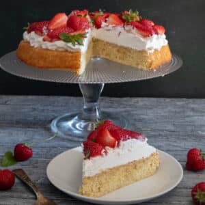 Strawberry crostata on a glass plate with a slice on a white plate.