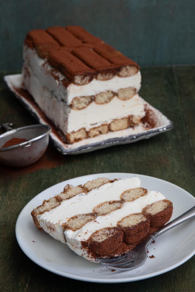 Tiramisu semifreddo on a white plate and a slice on a plate.