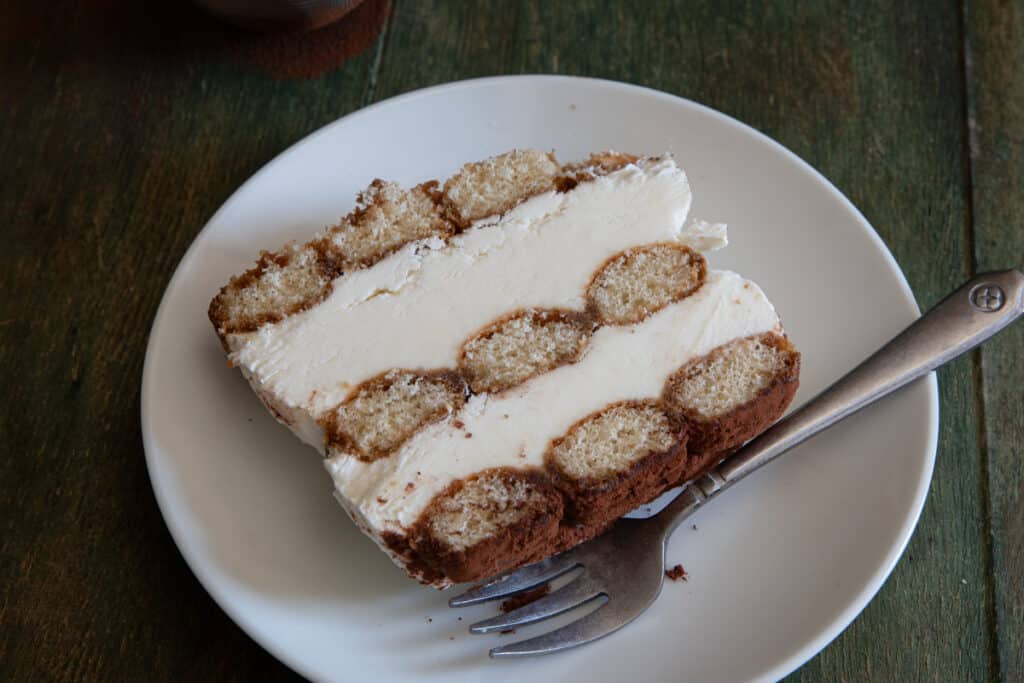 A slice of tiramisu on a white plate.