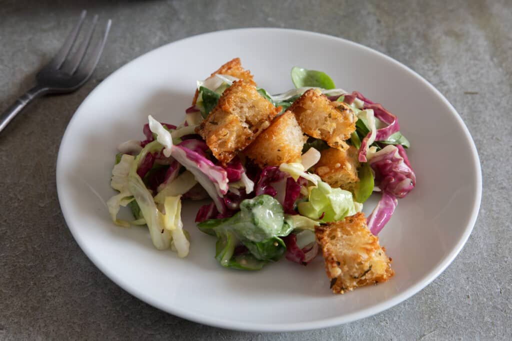 Croutons on a salad on a white plate.