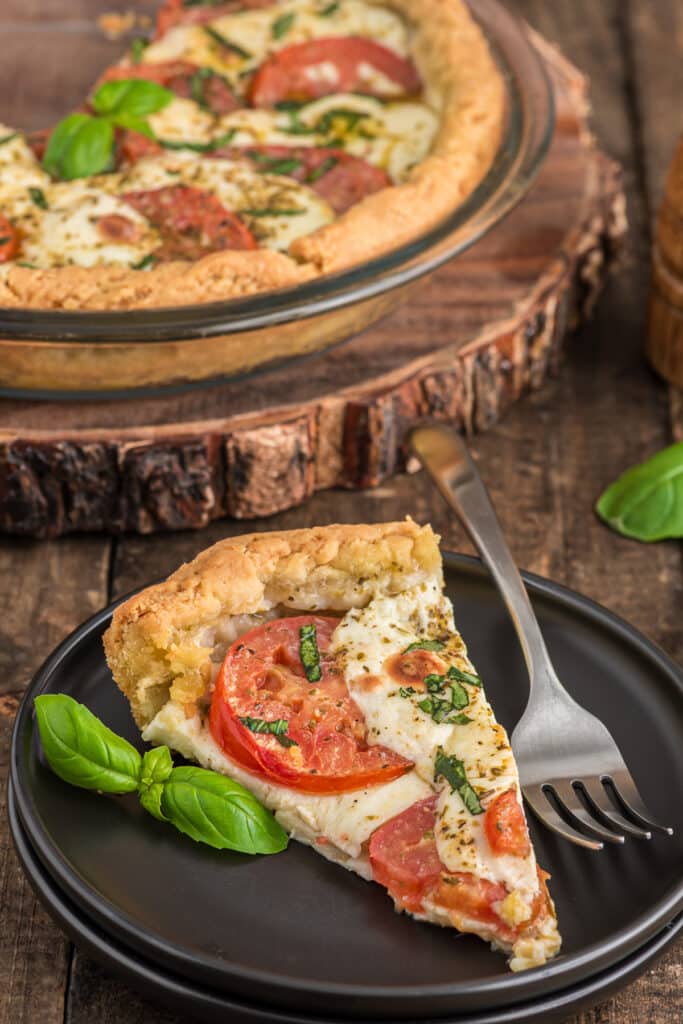 Caprese crostata in a glass pan and a slice on a black plate.