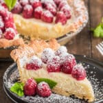 A slice of raspberry tart on a black plate.
