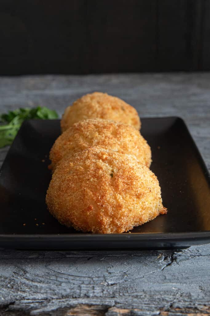 Three rice balls on a black tray.