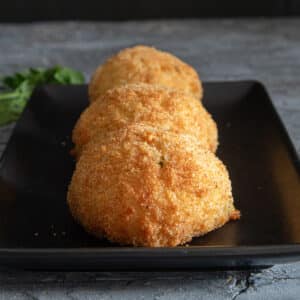 Three rice balls on a black tray.