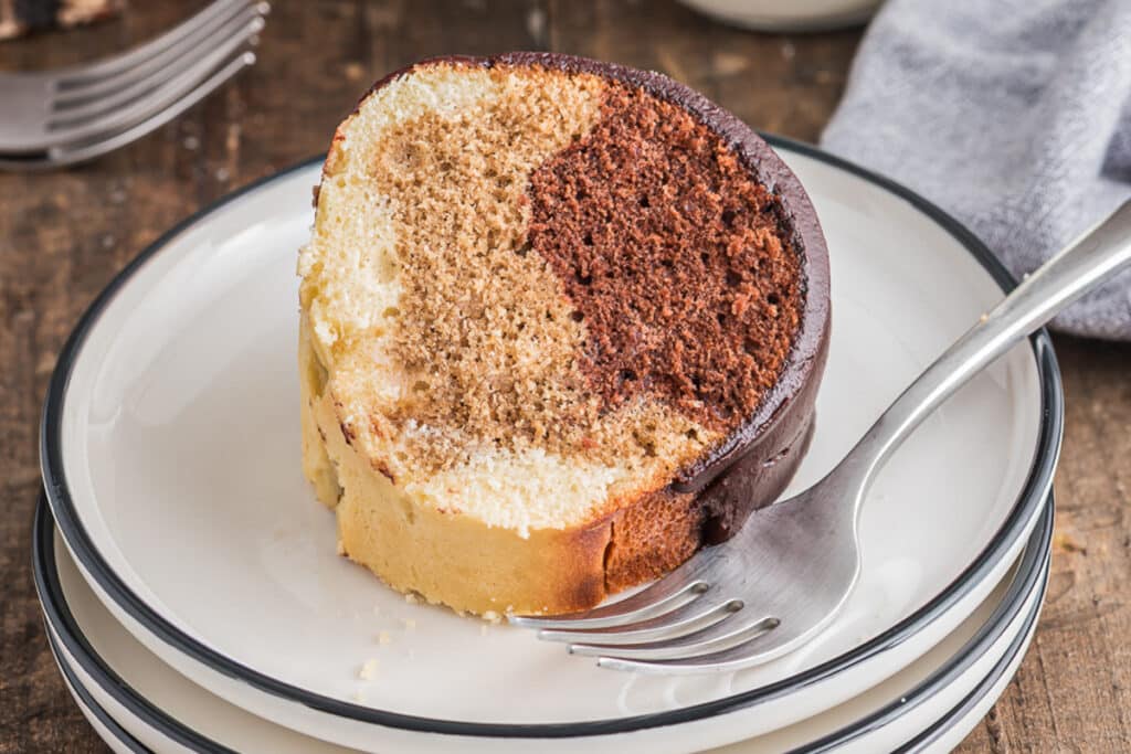 A slice of cake on a white plate with a fork.