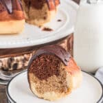 Bundt cake on a white stand with a slice on a white plate.