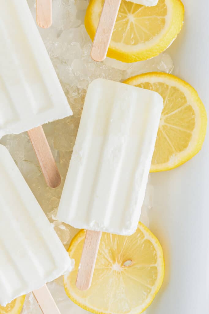 Lemon popsicles on lemon slices in a white tray.