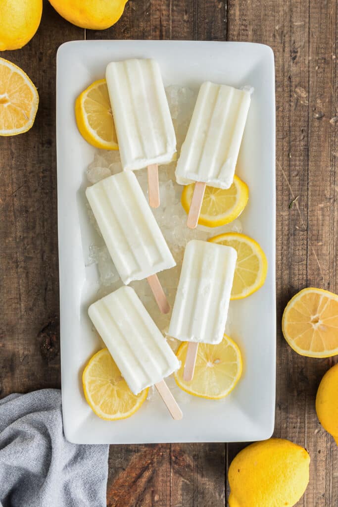 Popsicles on a white plate with lemon slices.