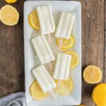 Popsicles on a white plate with lemon slices.