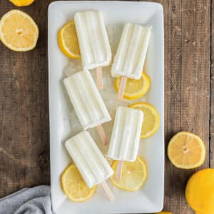 Popsicles on a white plate with lemon slices.