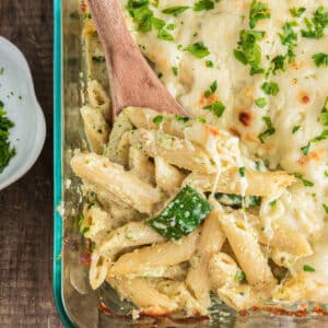 Zucchini baked pasta in a glass pan with a wooden spoon.