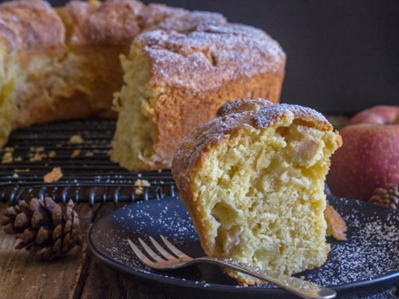 Apple cake on a wire rack with a slice cut.