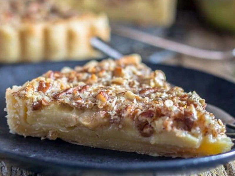 A slice of apple crostata on a black plate.