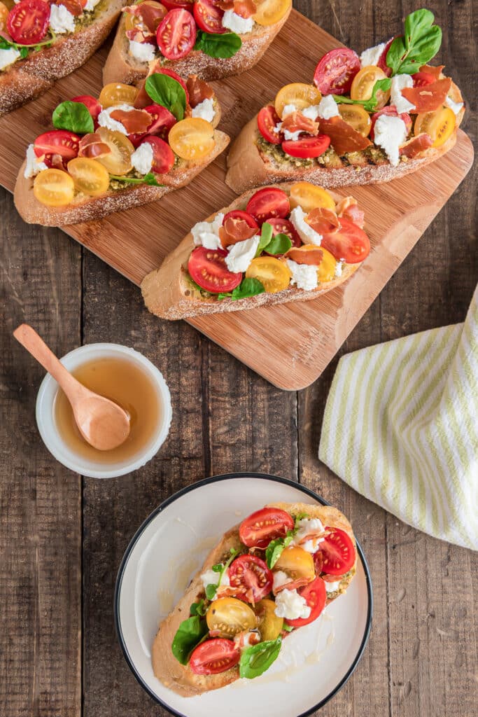 Prosciutto bruschetta on a wooden board and one on a plate.