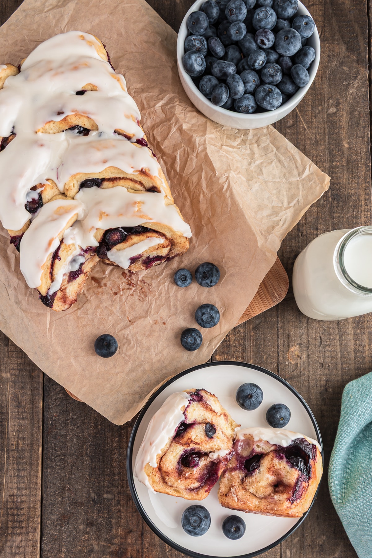 Blueberry bread on paper with a slice on a white plate.