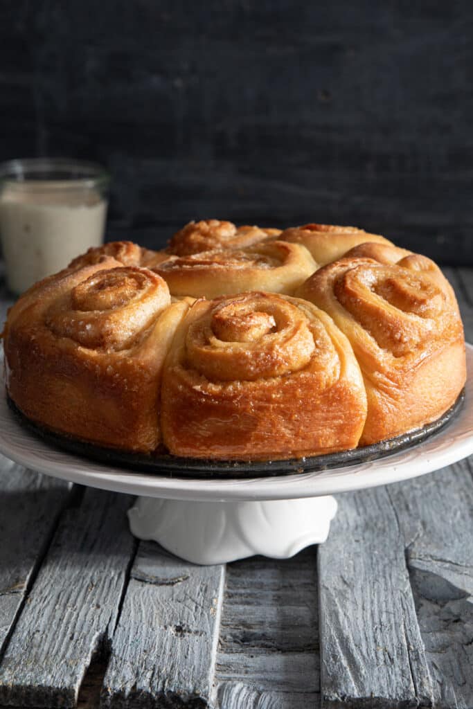 Unfrosted cinnamon buns on a white cake stand.