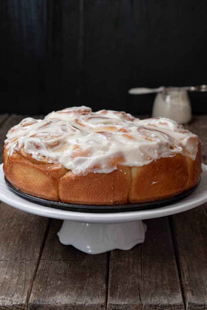 Lievito madre cinnamon buns on a white cake stand.