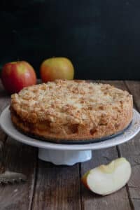 A crumb cake on a white cake stand.