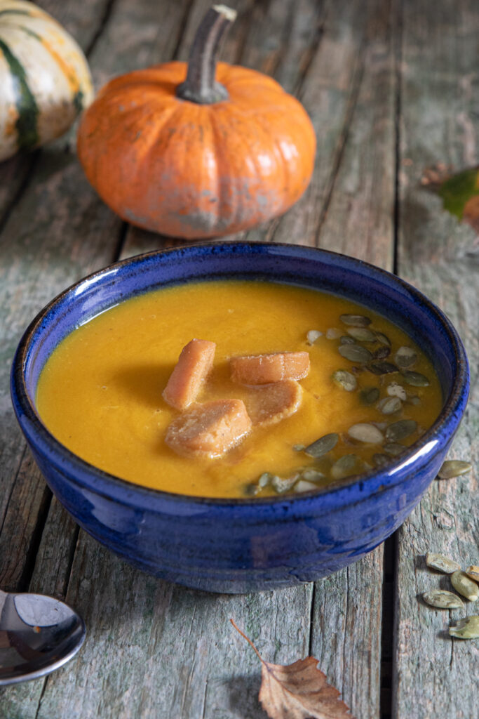 Carrot squash soup in a blue bowl.