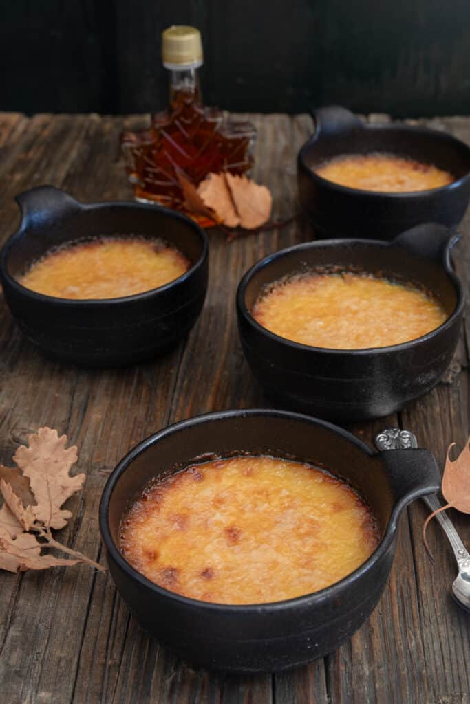 Four creme brulee on a wooden board.