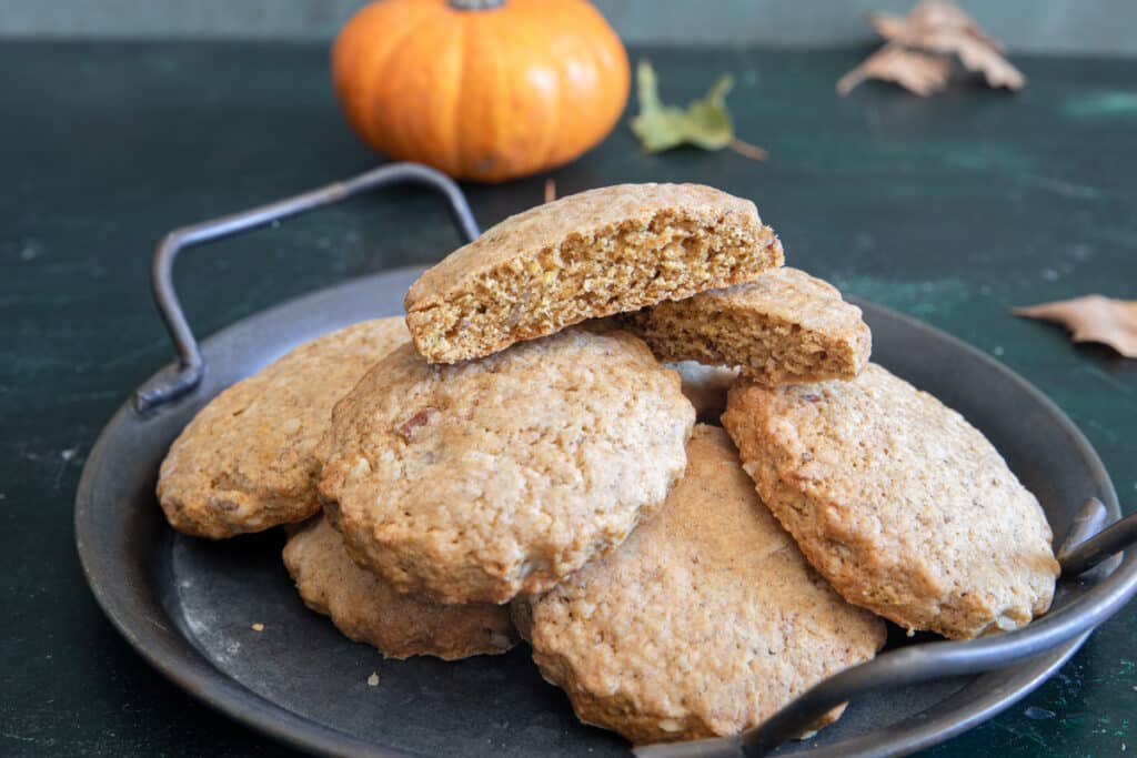 Pumpkin cookies on a black plate with one cut in half.