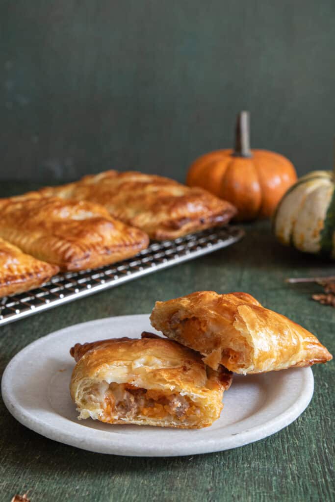 The hand pies on a wire rack and one cut on a white plate.