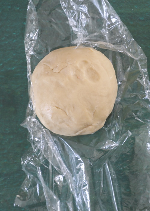 Wrapping the dough in plastic wrap.