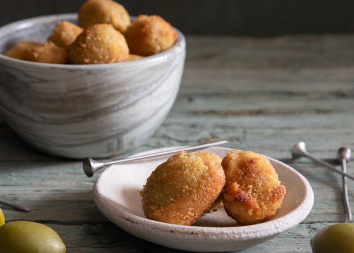 Olives in a bowl and two on a plate.