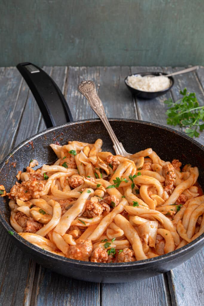 Strozzapreti with sauce in the pan.