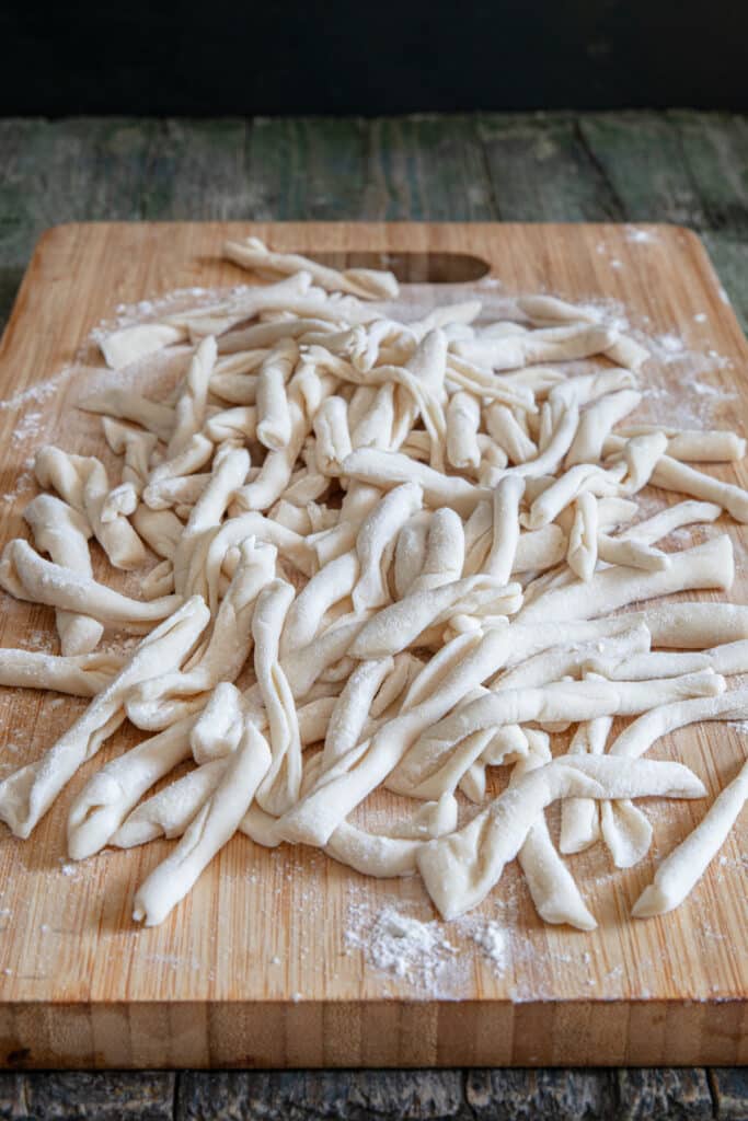 Strozzapreti pasta on a wooden board.