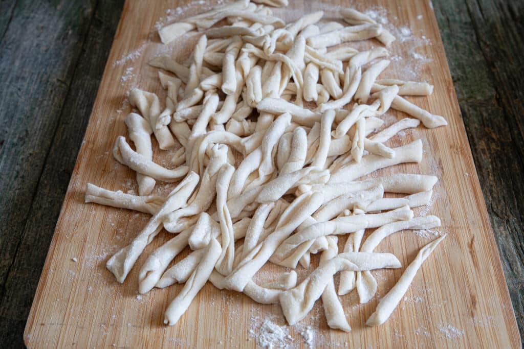 Strozzapreti pasta on a wooden board.