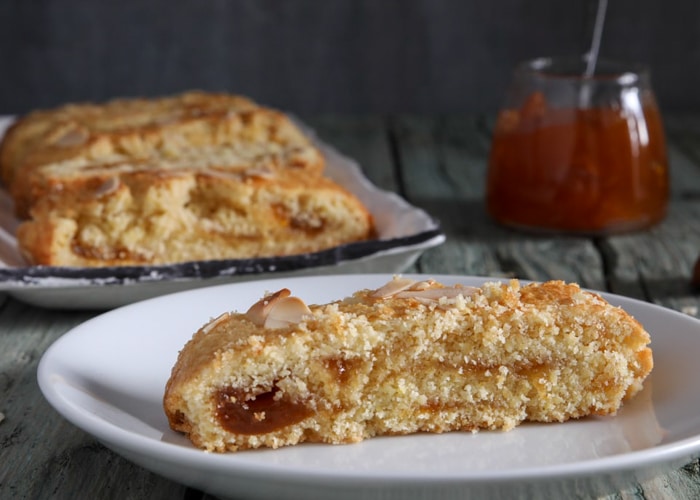 Almond roll with a slice cut on a white plate.