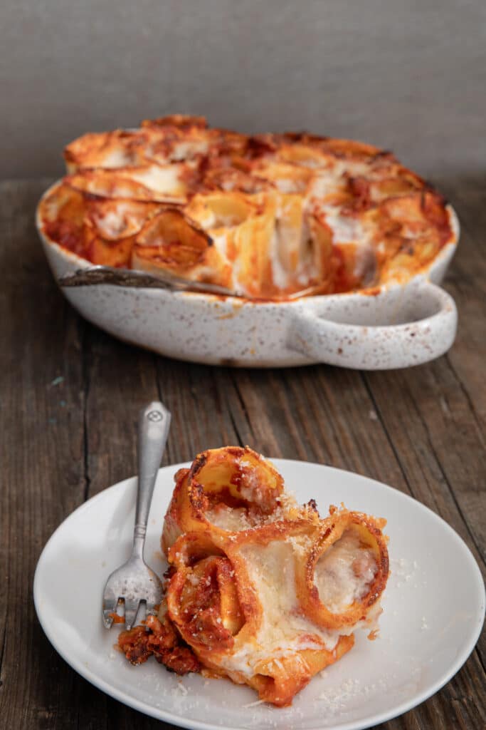 Lasagna rolls in the pan and three on a white plate.