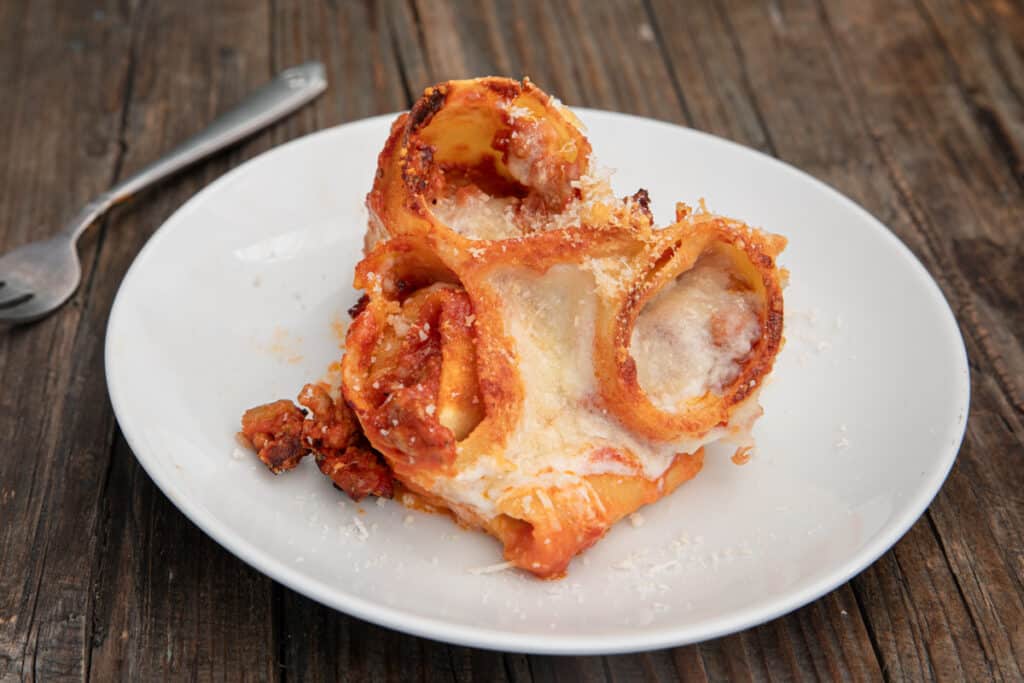 Three lasagna rolls on white plate.