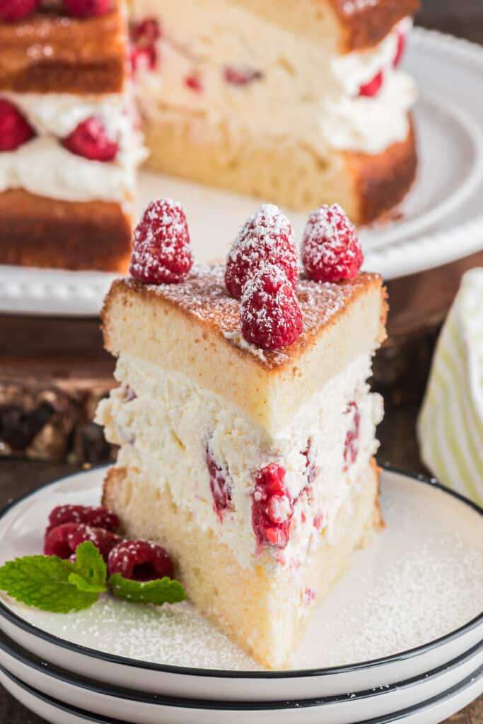 Layered cheesecake on a white plate with a slice on a small white plate.
