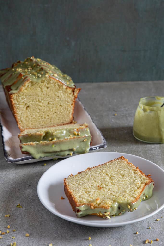 Pistachio sweet bread on a white plate with a slice on a round plate.