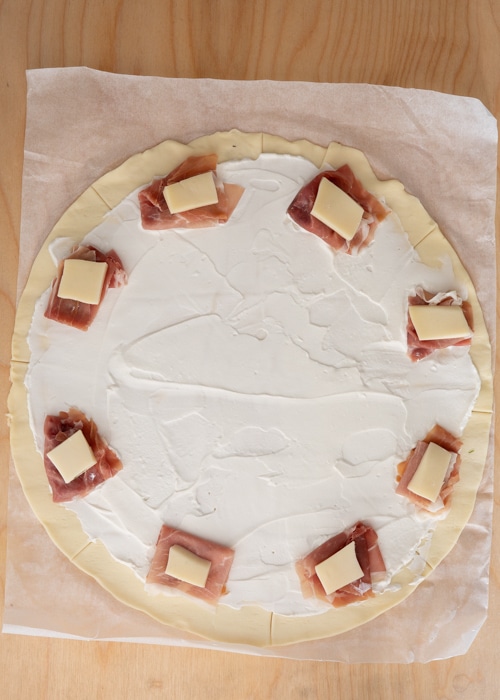 Spreading the ricotta and adding the prosciutto and cheese.