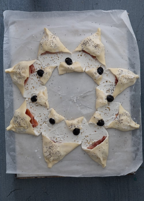 Closing the ends and sprinkling with oregano, seeds and adding olives.