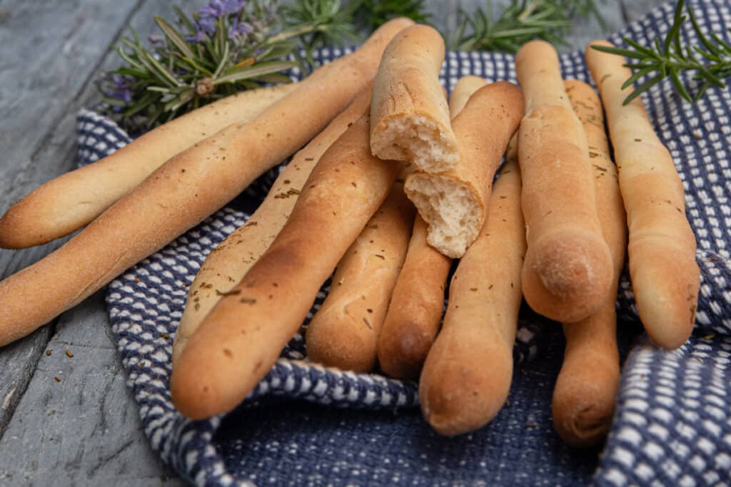 Grissini on a blue napkin with one cut in half.