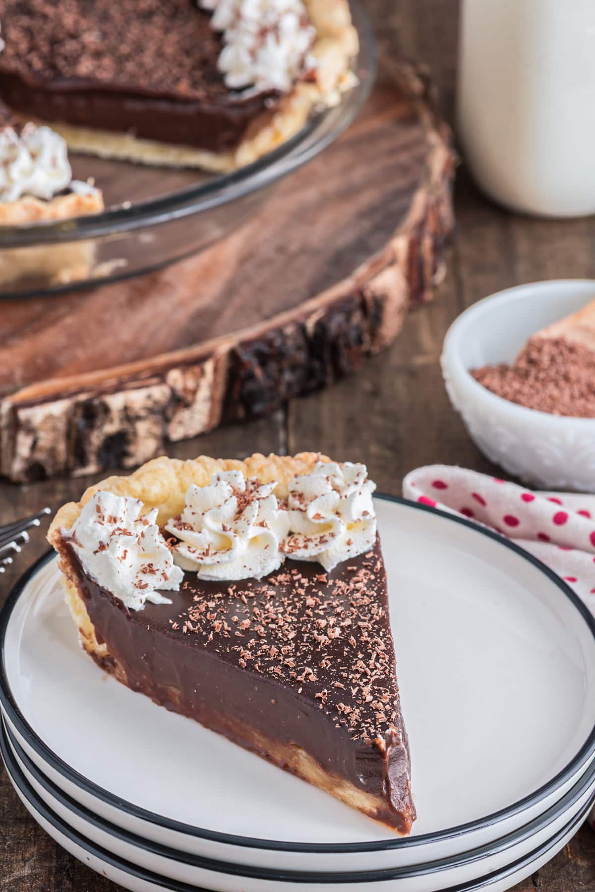 Chocolate cream pie in the pan and a slice on a white plate.