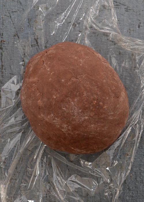 The dough rolled into a ball on plastic wrap.