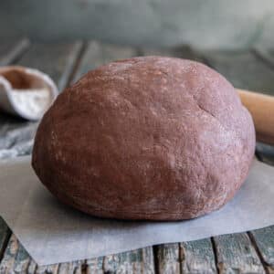 Chocolate pie dough on a piece of waxed paper.