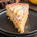 A slice of cake on a black plate.
