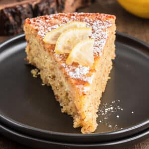 A slice of cake on a black plate.