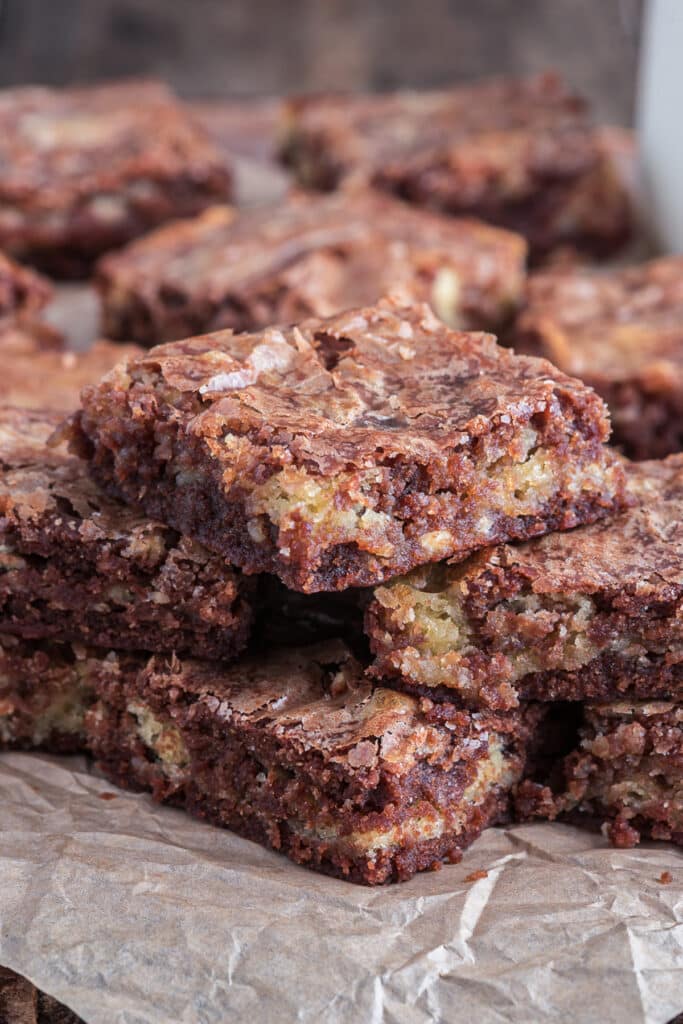 Brownies stacked on brown paper.