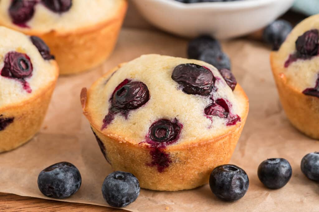 Blueberry muffins on a piece of brown paper.