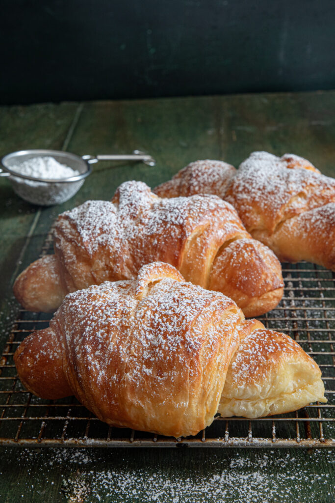Three cornetti on a wire rack.